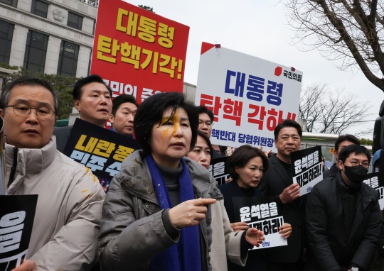 백혜련 더불어민주당 의원이 20일 서울 종로구 헌법재판소 앞에서 열린 당 원내부대표단의 윤석열 대통령 신속 파면 촉구 기자회견에서 얼굴에 달걀을 맞은 채 회견을 이어가고 있다. [연합뉴스]